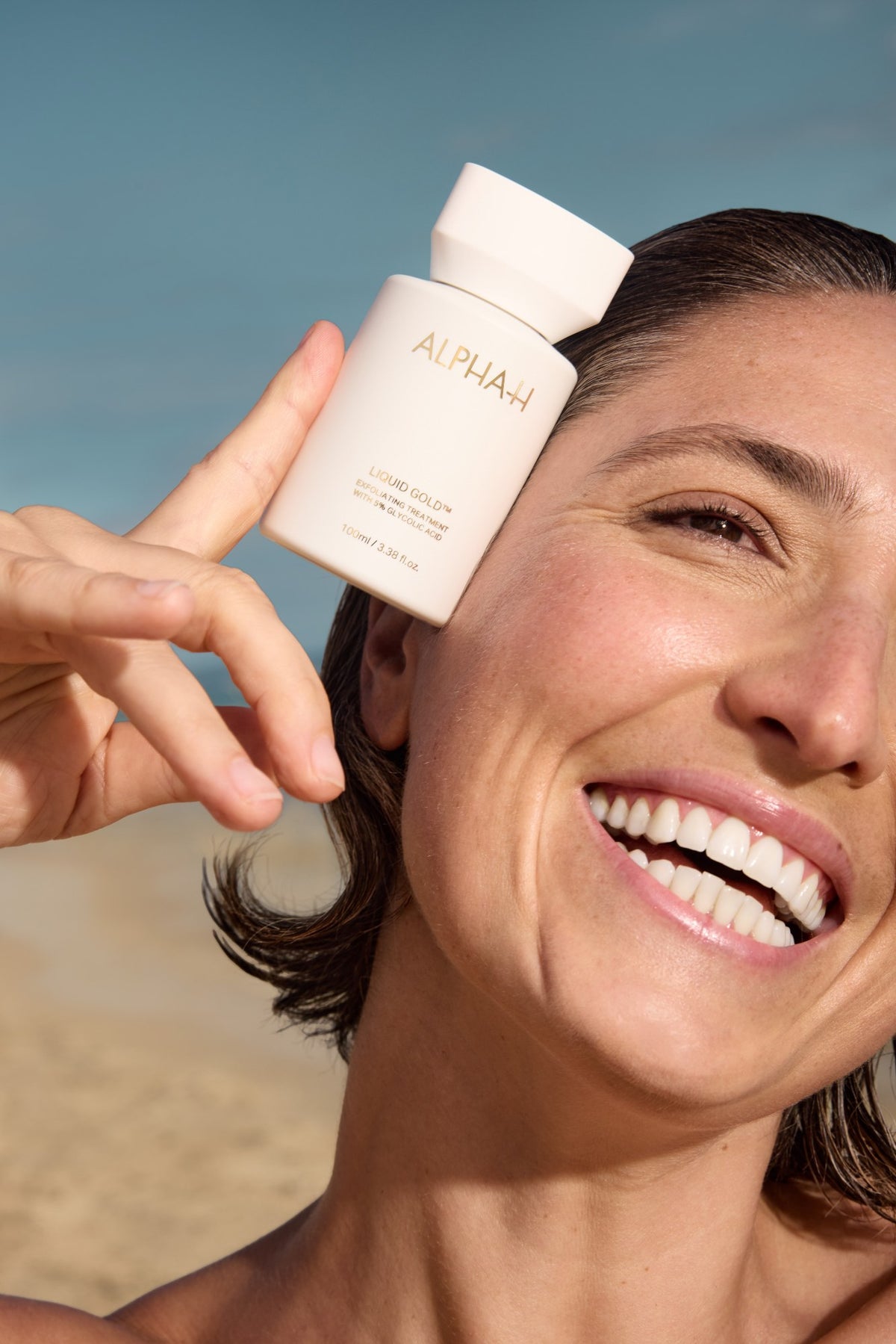 Alpha-H Liquid Gold Exfoliating Treatment model met flacon aan zee