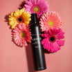 Oolaboo Glam Former Dry Shampoo tussen roze gerbera's