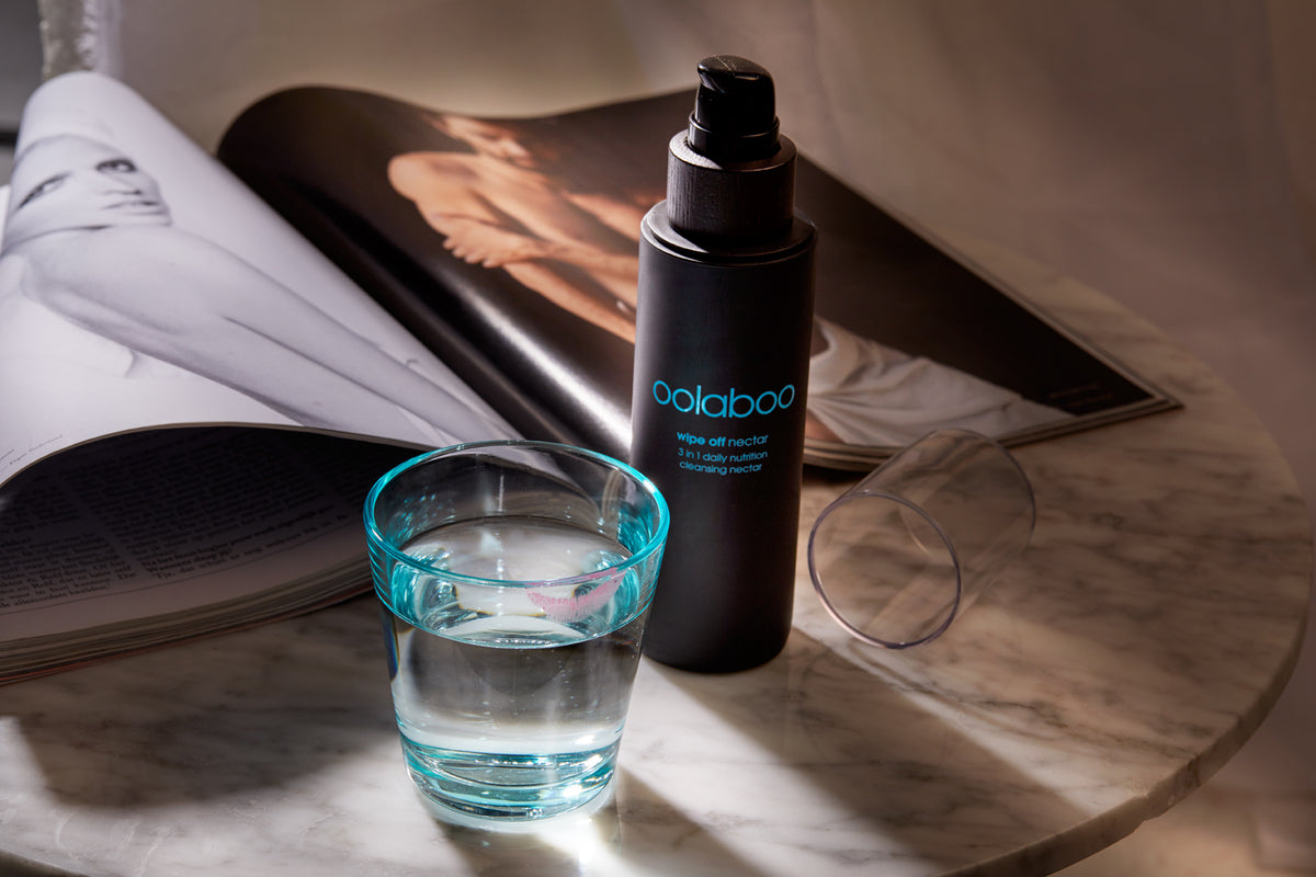 Oolaboo Wipe Off Nectar op marmer met een glas water